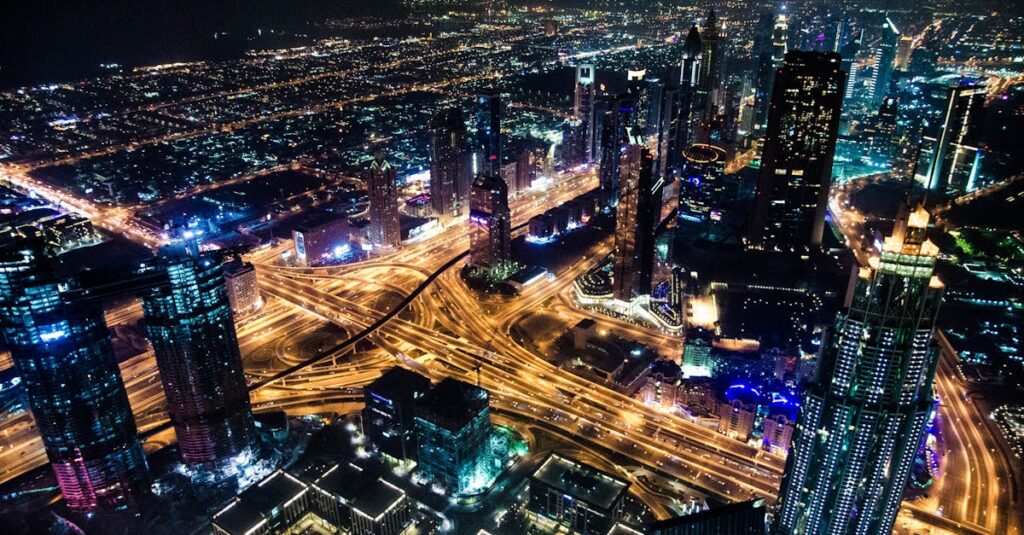 A stunning aerial view of Dubai's illuminated skyline at night, showcasing its modern architecture and busy roads.