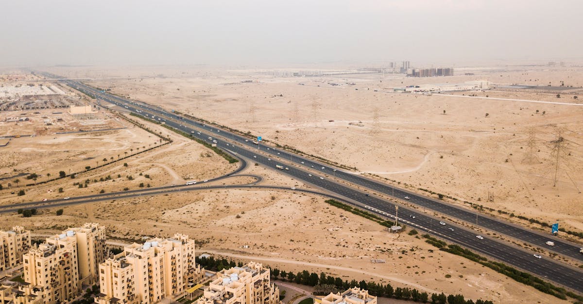 Drone shot of a highway through Dubai's desert landscape with buildings below.