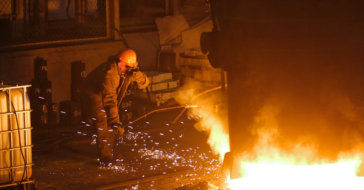 A steelworker in a factory welding near molten metal, showcasing industrial hard work.